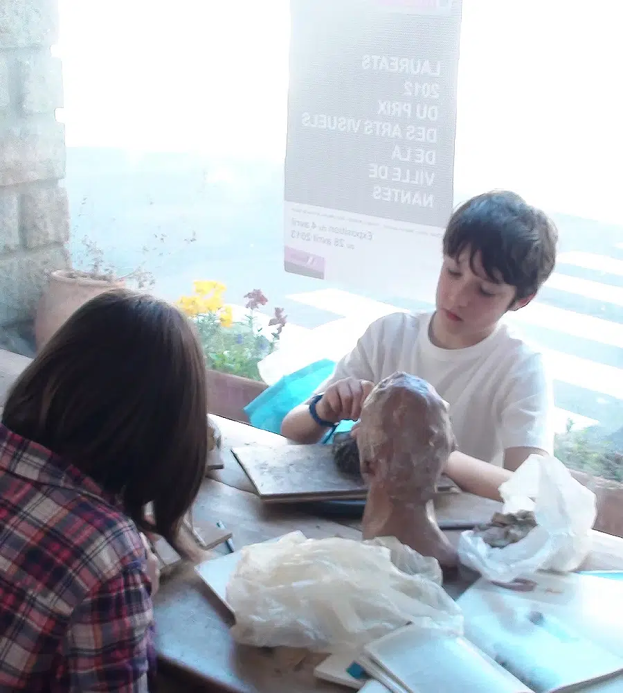 Enfants sculptant une tête en argile